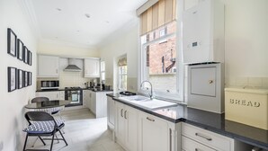 Een moderne keuken met witte kasten, een zwart aanrecht en een raam met uitzicht op een bakstenen gebouw.