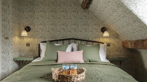Ein Schlafzimmer mit grüner Bettdecke, einem Korb mit Croissants und zwei Nachttischlampen.