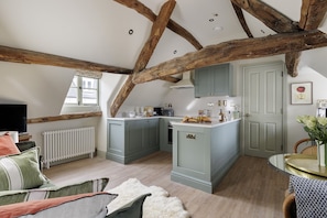 Une pièce confortable de style loft, avec des poutres apparentes, un coin cuisine, un espace salon agréable et une vue sur la ville.