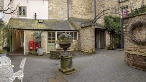 Ein Innenhof mit Steingebäuden, einer grünen Tür und einer roten Telefonzelle.
