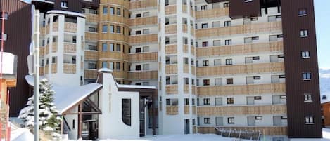 A multi-story hotel with a modern design, featuring balconies and a central entrance.