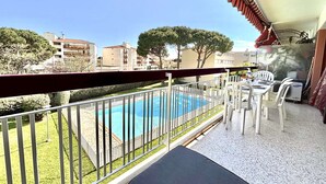 A balcony with a pool, white chairs, and a table. - 3-bedroom apartment in Fréjus with shared pool, near the center (Fréjus)