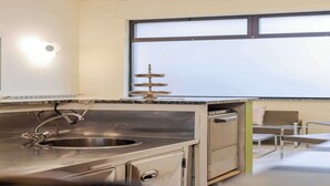 Una cocina moderna con un lavamanos de acero inoxidable, horno integrado y una ventana con persianas.