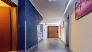 Un pasillo con piso de madera, pared azul y una puerta de madera al final.