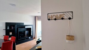 Una sala moderna con un mueble de entretenimiento negro, sillas rojas y un letrero que dice 'HOME' montado, con una cesta colgante.
