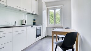 Een moderne keuken met witte kasten, een ingebouwde oven en een raam dat voor natuurlijk licht zorgt.