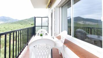 Un balcón con una mesa y sillas, una planta en maceta y vistas a un paisaje montañoso.
