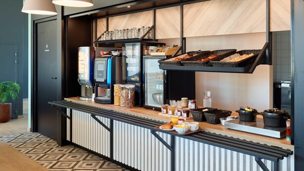 Ein Frühstücksbuffet mit einer Kaffeemaschine, Brötchenkörben und verschiedenen Frühstücksangeboten.