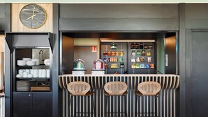 Eine Bar mit einer Uhr, Flaschenregalen und drei Barhocker.