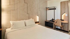 Ein Hotelzimmer mit einem Bett, Nachttischen, einem Schreibtisch mit Stuhl und einem Spiegel.