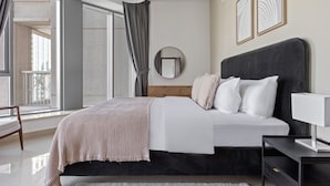 A modern bedroom with a large bed, a bedside table, a hanging light, and a view of the outside balcony.