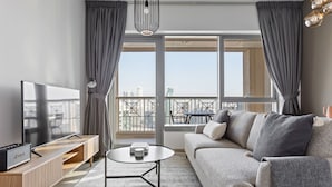 A modern living room with a sofa, TV, and a balcony with a city view.