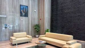 Eine moderne Lobby mit einem beigefarbenen Sofa, einem Couchtisch und einer großen Pflanze in einem Topf.