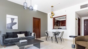 A modern living room with a grey sofa, a coffee table, and a dining area with chairs. - Blueground | Downtown Dubai, pool, nr Burj Khalifa (Dubai)