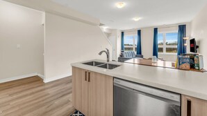 A modern kitchen with a dishwasher, a sink, and a window with curtains. - Stylish Niagara Falls Getaway with Rooftop City Views (Niagara Falls)