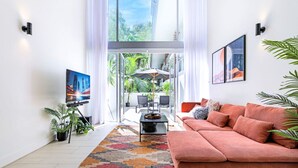 Un salon moderne avec une grande fenêtre, un canapé, une table basse et un téléviseur.