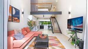 Un salon moderne avec un canapé, une table basse et un téléviseur posé sur un meuble.
