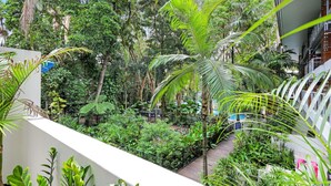 Un jardin intérieur luxuriant, avec une variété de plantes tropicales et un sentier en bois.