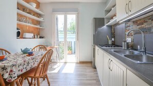 Une cuisine compacte comprenant un coin repas, un réfrigérateur, un évier et une fenêtre donnant sur un balcon.