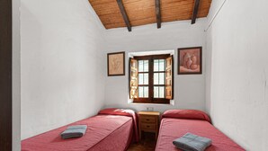 Un alojamiento pequeño, de una sola habitación, con dos camas, una ventana y techo de madera.