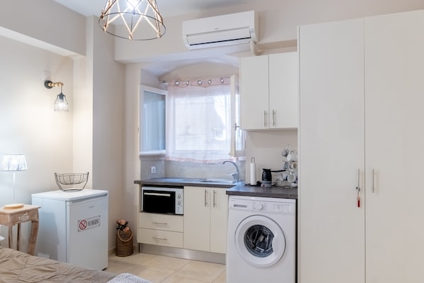 Une cuisine compacte équipée d’un lave-linge, d’un four à micro-ondes et d’un petit réfrigérateur.