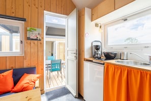 Cocina compacta con lavamanos, cafetera y ventana.