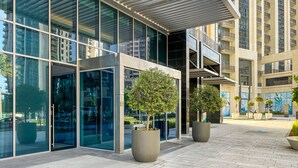 Un edificio moderno con amplios ventanales y un patio empedrado con árboles en macetas.
