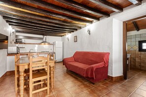 Uma cozinha com uma mesa de jantar e cadeiras, um sofá vermelho e um revestimento de azulejos.