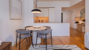 Une cuisine moderne avec un îlot central, un coin repas comprenant une table ronde et quatre chaises, et un grand miroir sur le mur.