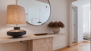 Une salle de bain moderne avec un miroir rond, une lampe au design original et une plante en pot posée sur un comptoir en marbre.