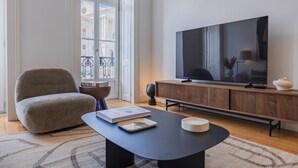 Un salon moderne doté d’un grand téléviseur à écran plat, d’un fauteuil confortable, d’une table basse et d’une bibliothèque.