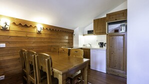 A compact kitchen with wooden cabinetry, a white countertop, and a built-in dishwasher. - Nice apt near the slopes for 6 pers (Modane)
