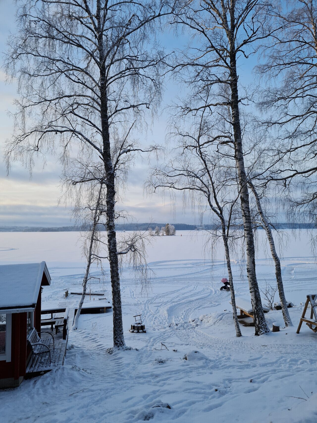 A snow-covered landscape with a wooden cabin and benches.