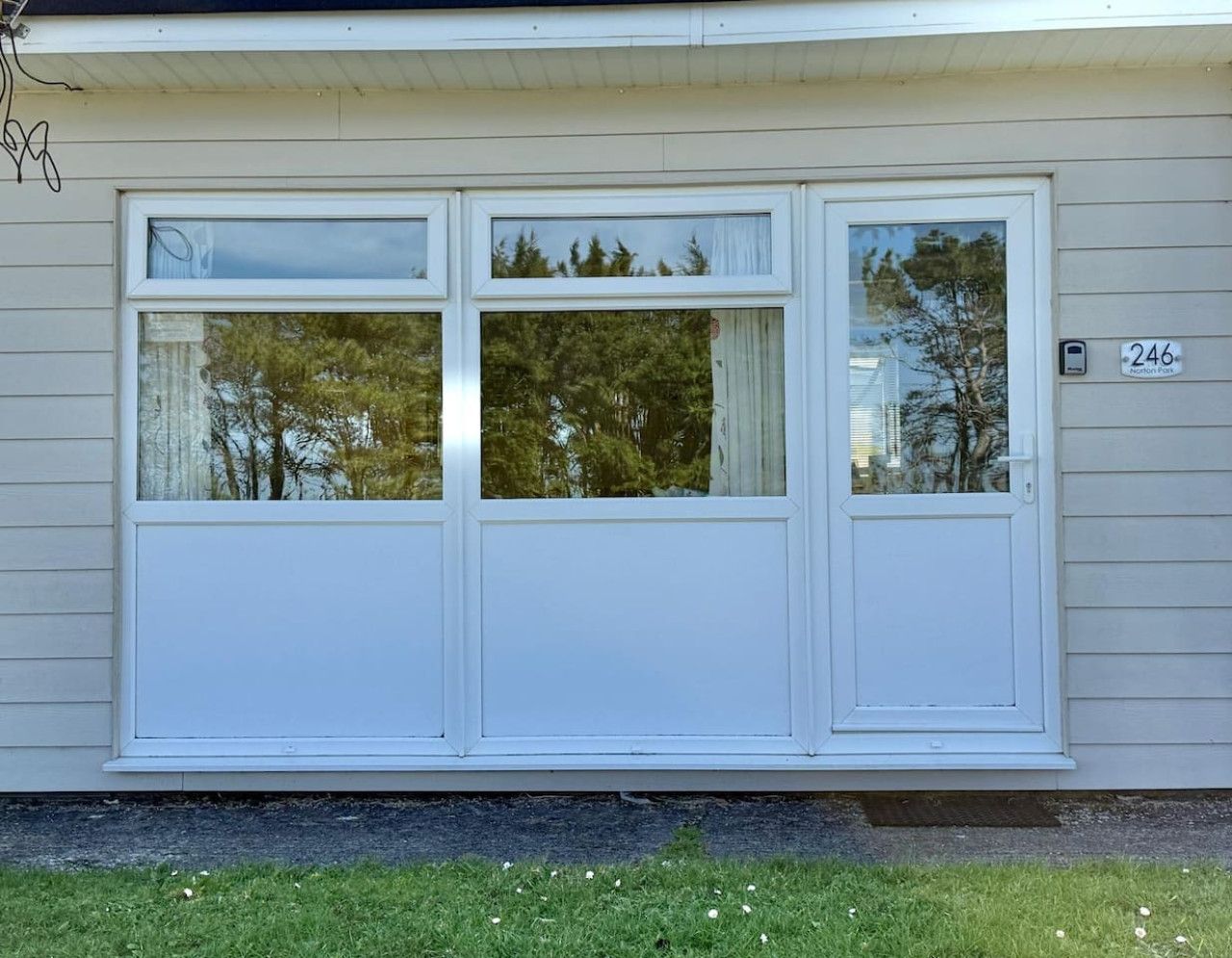 Een huis met een groot raam met een witte omlijsting en een brievenbus.