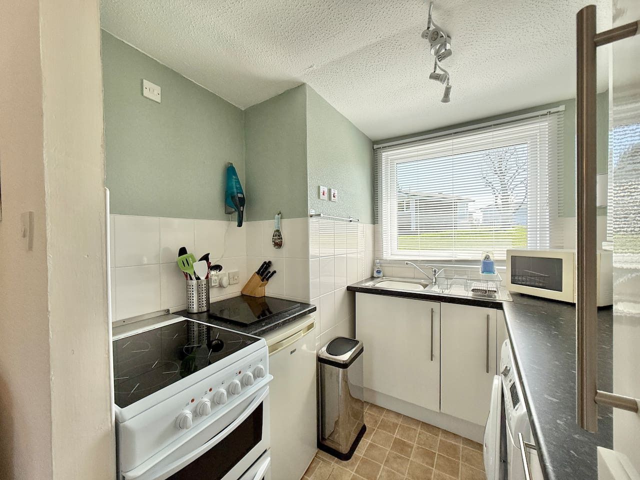 Een functionele keuken met een kookplaat, oven, spoelbak en een magnetron.