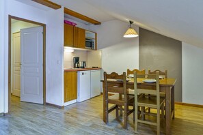 Una cucina compatta con mobili in legno, un forno a microonde e un tavolo con sedie.