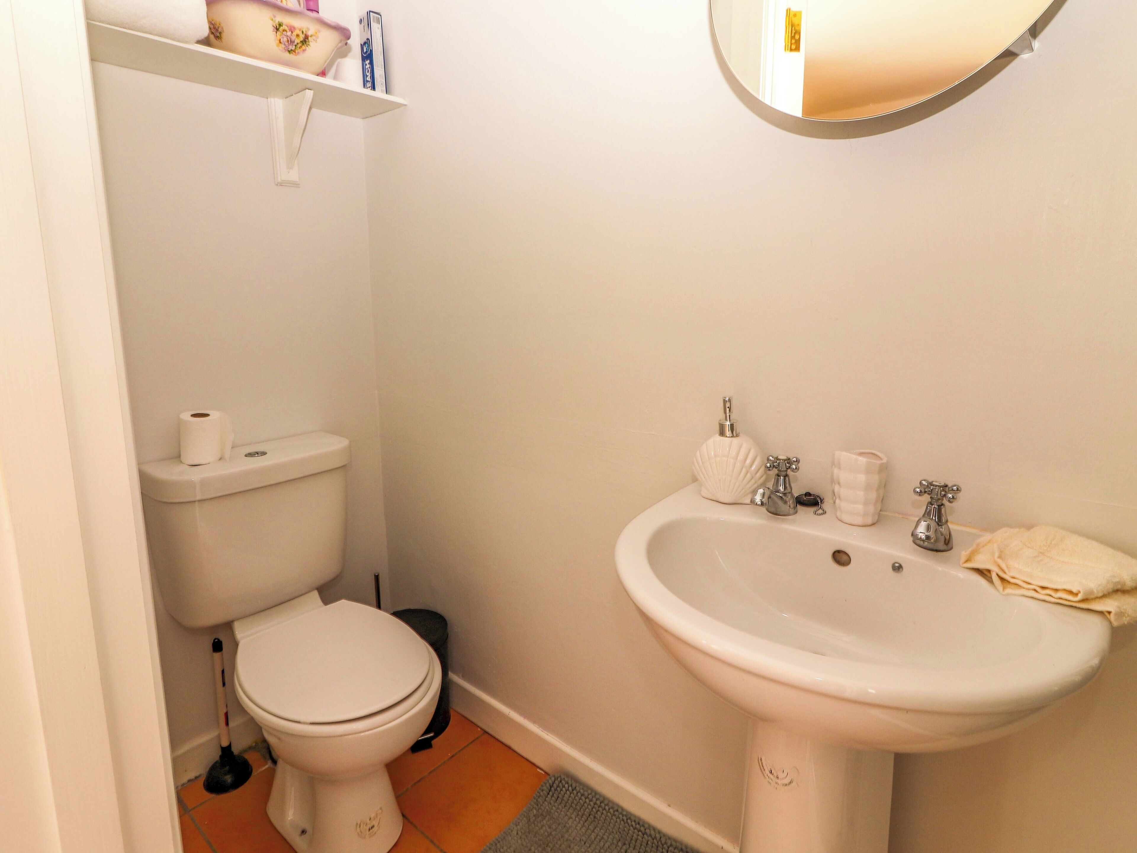 A bathroom with a toilet, sink, and a mirror.