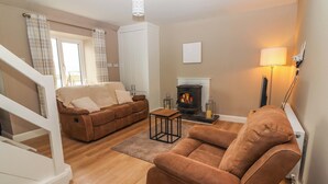 Una sala de estar acogedora con un sofá, un sillón y una chimenea.