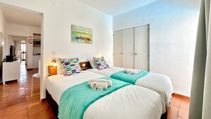 Een hotelkamer met twee bedden, een kitchenette en een badkamer.
