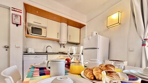 Een ontbijt met een koffiezetapparaat, theepot, croissants en sinaasappelsap.