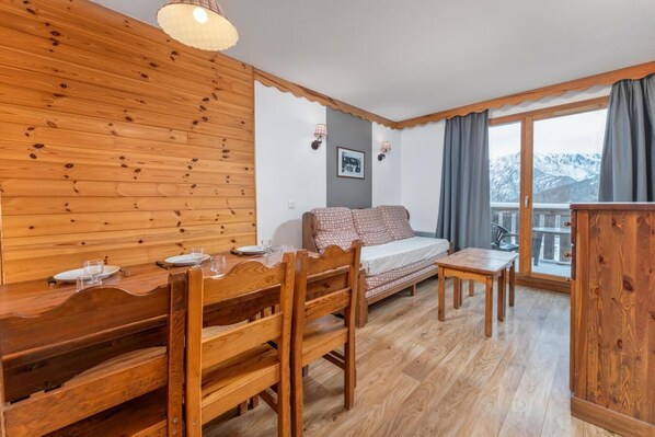 A cozy room with a wooden bench, a sofa, and a table. - Resort center, 1st floor, fitness, swimming pool, sauna, balcony, tv, ski locker, 38m², Les Orres (Les Orres)