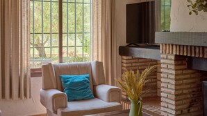 Ein Wohnzimmer mit Sofa, Couchtisch, Kamin aus Ziegelsteinen und einem fenster mit Vorhängen.