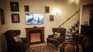 Un salon chaleureux avec une cheminée, deux fauteuils, un téléviseur et un escalier.