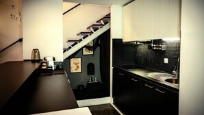 Une cuisine moderne avec des plans de travail sombres, un revêtement mural noir et des meubles blancs.