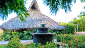 A thatched-roof structure surrounded by lush greenery and a central water feature. - Casa Torre Del Cielo / Ocean Views, Pool & Privacy (Careyes)
