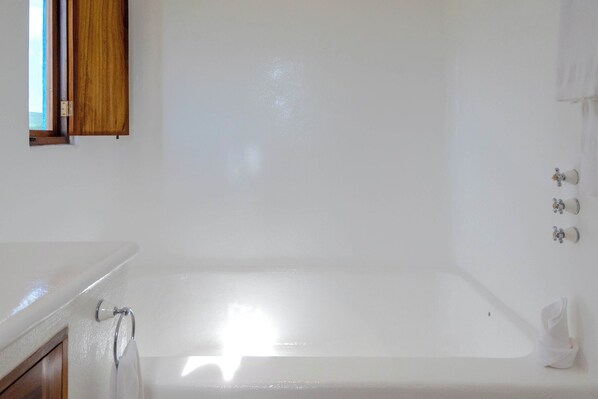 A bathroom with a bathtub, a wooden door, and a towel rack.