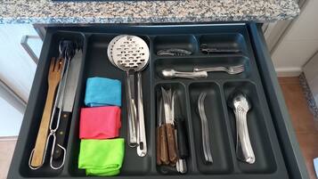 A kitchen drawer with utensils and cloths.