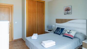 Une chambre à coucher avec un lit, une armoire en bois, une table de chevet, une lampe et un tableau accroché au mur.
