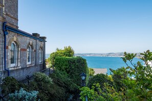 A stone building with arched windows and a view of the sea.