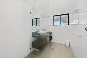 A modern bathroom with a glass shower enclosure, two sinks, and a window with a view. - Absolute Beachfront Beauty (Gold Coast)